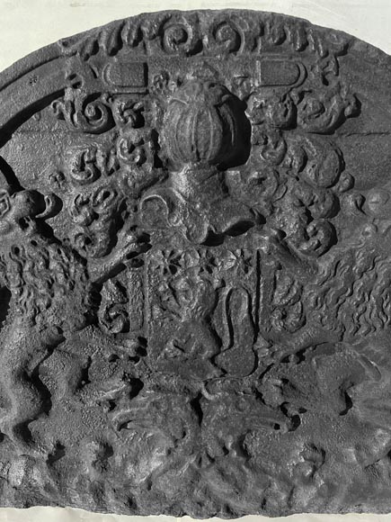 A semicircular cast iron fireplace plaque, decorated with a coat of arms, surmounted by a helmet and framed by lions.-2